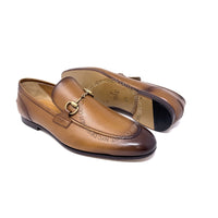 Pair of brown leather loafers with a gold buckle on a white background