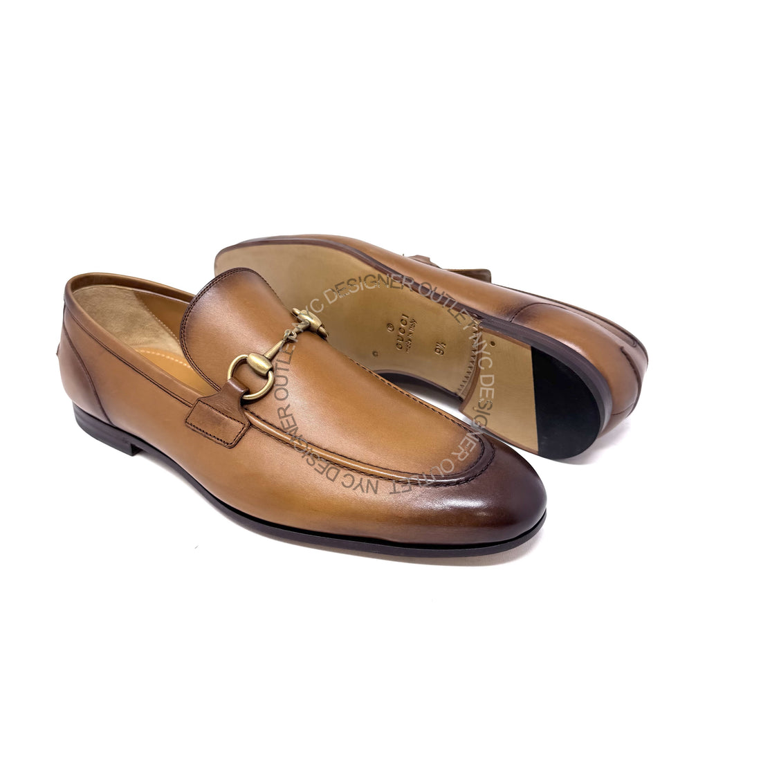 Pair of brown leather loafers with a gold buckle on a white background